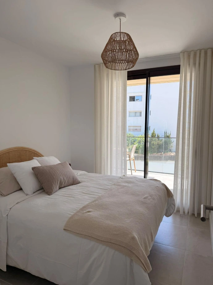 Dormitorio luminoso con cortinas blancas a medida y cama tapizada